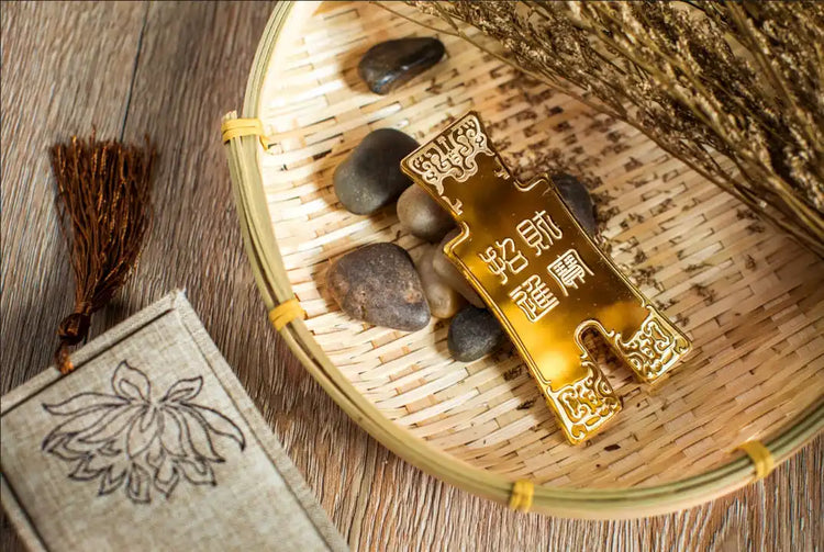 A gold-colored, rectangular ingot-shaped ornament with decorative patterns and Chinese characters.